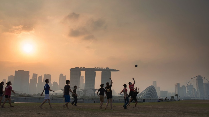 黃昏時(shí)分，一群男孩在濱海堤壩 (Marina Barrage) 上踢足球，遠(yuǎn)處是濱海灣的朦朧輪廓